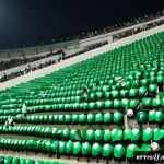 사우디아라비아 축구리그  사우디 프로 리그 - A dynamic scene of a Saudi Arabian football stadium filled with enthusiastic fans waving flags and w...